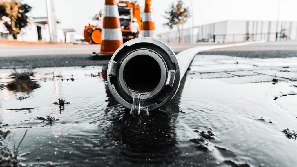 Insurance for Sewer and Watermain Contractors blog image of a gray pipe with water spewing out of it